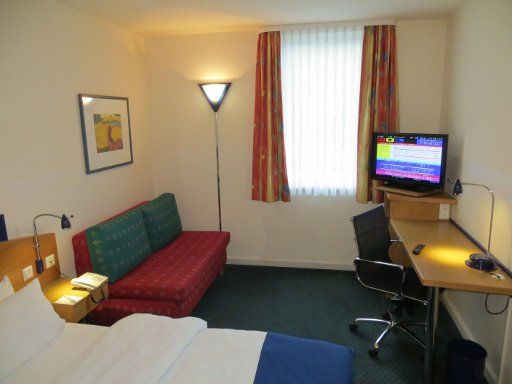 Holiday Inn Express® Dortmund, Deutschland, Zimmer 102 mit Doppelbett, Nachttischleuchten, Sofa, Fenster, Flachbildfernseher, Bürostuhl und Schreibtisch