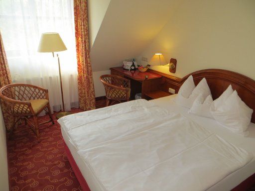 H+ Hotel Nürnberg (ehemals Ramada® Landhotel Nürnberg), Deutschland, Zimmer 202 mit Doppelbett, Fenster, Stehlampe, zwei Stühlen, Schreibtisch und Minibar