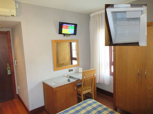 Adeko Hotel, El Regato - Barakaldo, Spanien, Zimmer 201 mit Eingangstür, Klimaanlage, Flachbildfernseher, Spiegel, Tisch, Kühlschrank und Stuhl