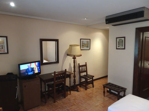 Gran Hotel Castellano Centro, Salamanca, Spanien, Zimmer 401 mit Fernseher, Kühlschrank, Schreibtisch, Stuhl, Klimaanlage, Kofferablage, Eingang und Tür zum Badezimmer